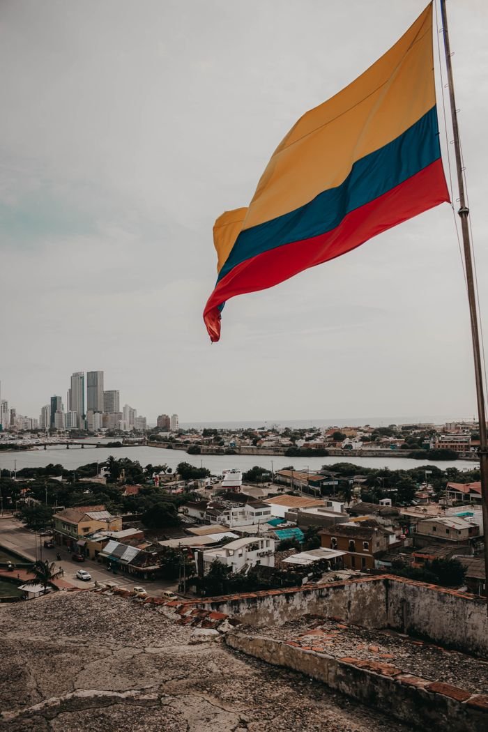 Colombian flag waving over urban landscape with skyline view.